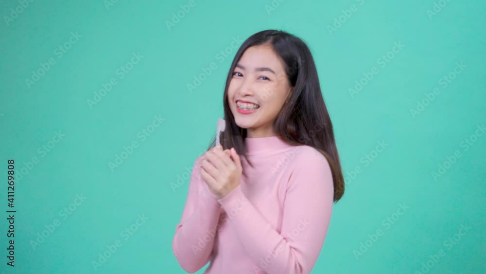 Smiling young asian woman wearing braces retainers with brushing teeth dancing enjoying music Smiling young asian woman wearing braces retainers with brushing teeth dancing enjoying music