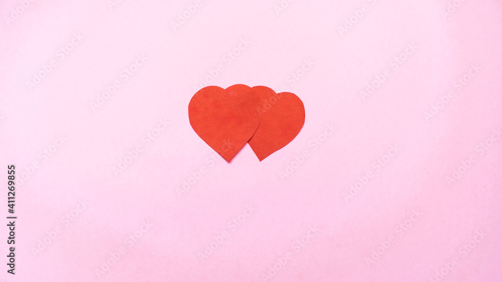 Two red hearts as symbol of love isolated on light pink background.