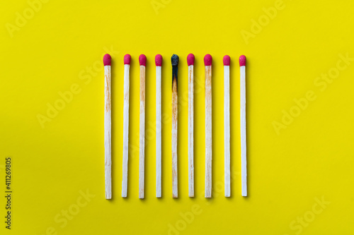 Success  defeat  achievement. The concept of happiness. Matches on a yellow background. Burnt dark match among normal matches. Burning match fire to its neighbors  a metaphor for ideas and inspiration