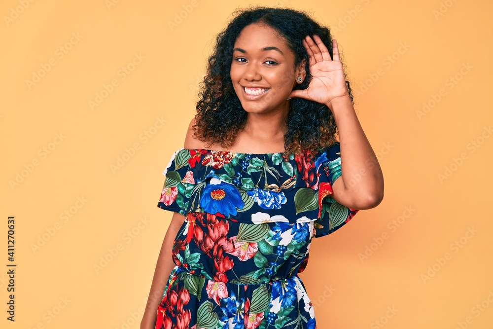 Young african american woman wearing casual clothes smiling with hand over ear listening an hearing to rumor or gossip. deafness concept. Young african american woman wearing casual clothes smiling with hand over ear listening an hearing to rumor or gossip. deafness concept.