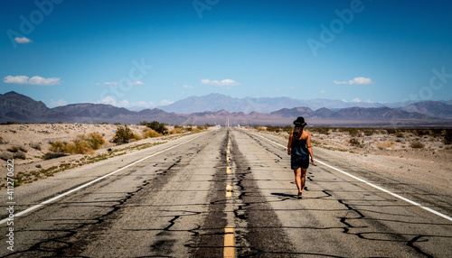 Eine junge Frau läuft entlang der endlos anmutenden Route 66 welche quer durch die USA führt. photo