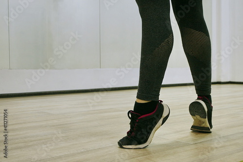 Sporty woman in sneakers does exercise in the dance hall.