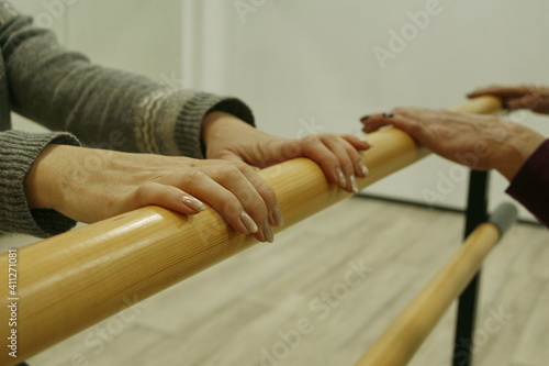 Female hands on the ballet barre. Dance rehearsal.
