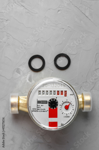 New hot water meter with two rubber gaskets on a gray concrete background.