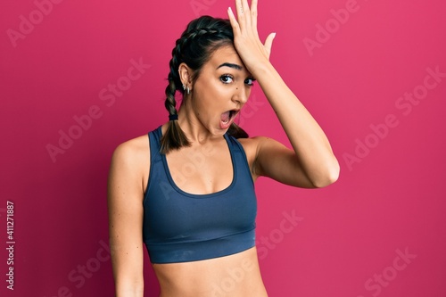 Young brunette girl wearing sportswear and braids surprised with hand on head for mistake, remember error. forgot, bad memory concept. © Krakenimages.com