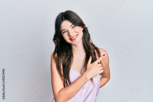 Young beautiful caucasian girl wearing casual clothes smiling cheerful pointing with hand and finger up to the side