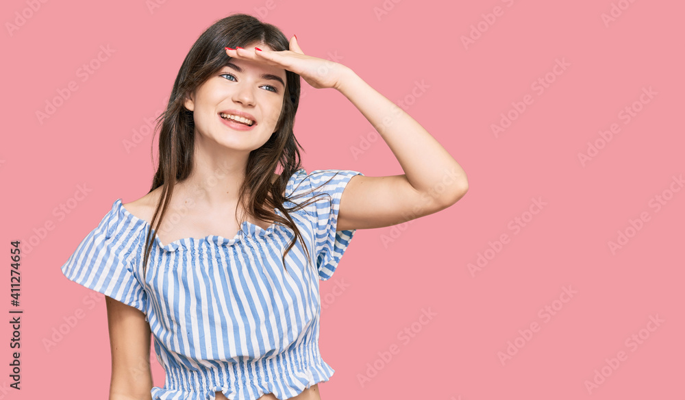 Young beautiful caucasian girl wearing casual clothes very happy and smiling looking far away with hand over head. searching concept. Young beautiful caucasian girl wearing casual clothes very happy and smiling looking far away with hand over head. searching concept.