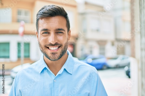 Young hispanic man smiling happy standing at street of city.