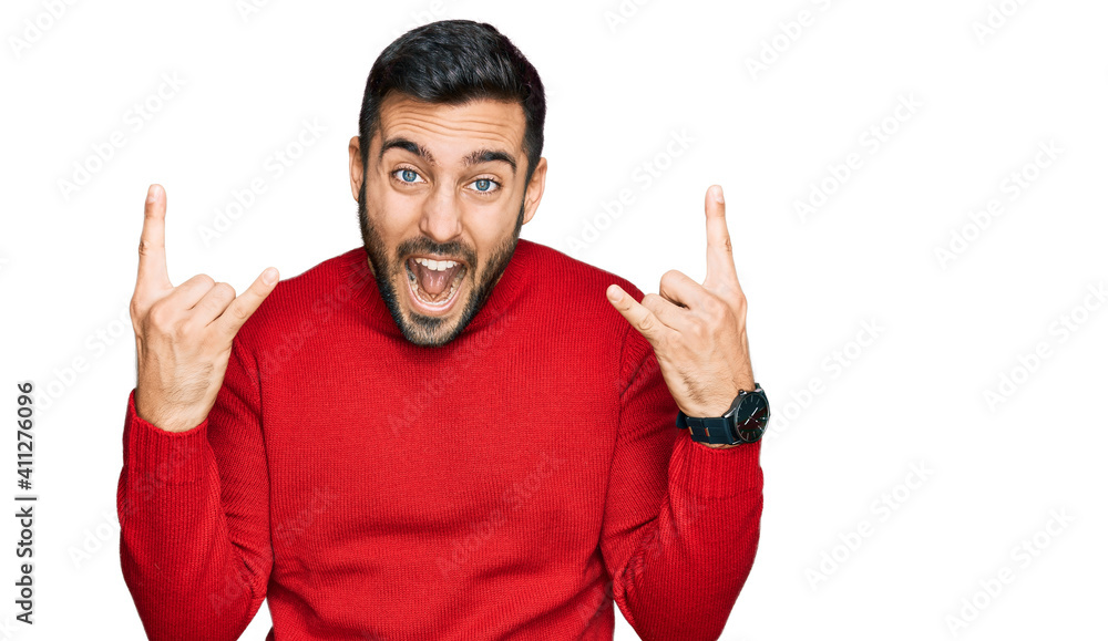 Fototapeta premium Young hispanic man wearing casual clothes shouting with crazy expression doing rock symbol with hands up. music star. heavy music concept.