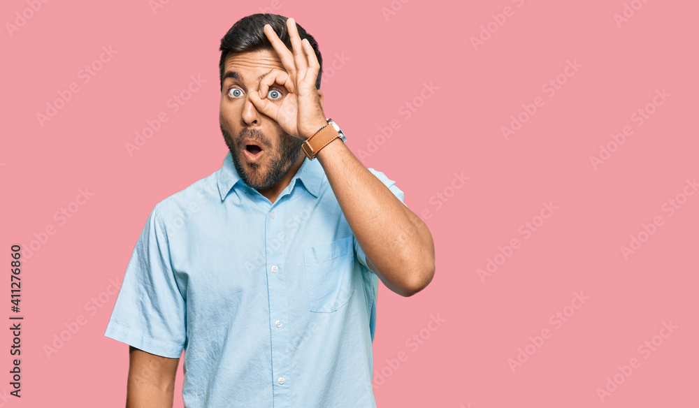 Handsome hispanic man wearing casual clothes doing ok gesture shocked with surprised face, eye looking through fingers. unbelieving expression. Handsome hispanic man wearing casual clothes doing ok gesture shocked with surprised face, eye looking through fingers. unbelieving expression.