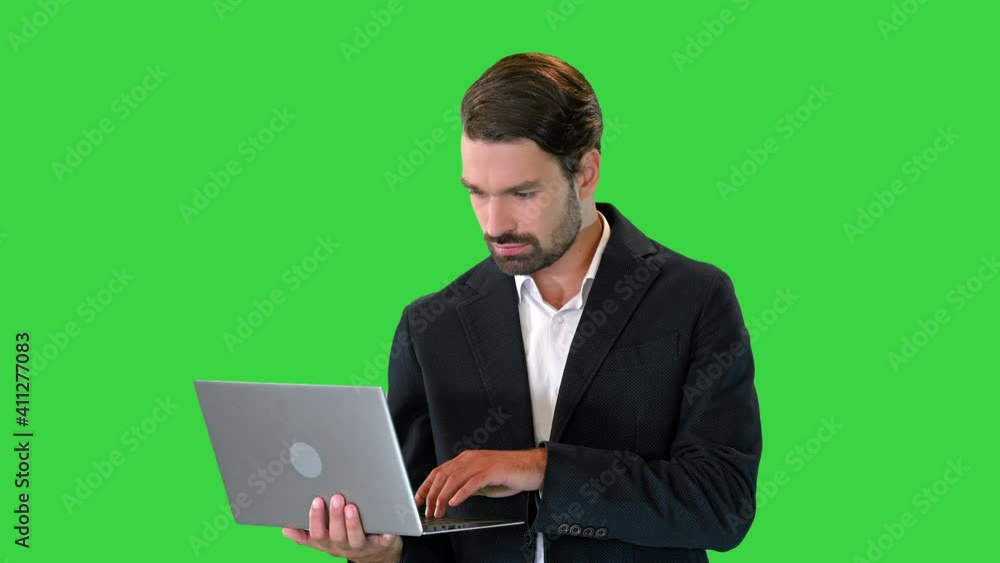 Young standing business man working on a laptop on a Green Screen, Chroma Key. Young standing business man working on a laptop on a Green Screen, Chroma Key.