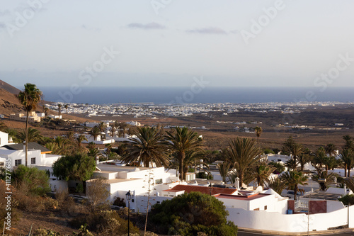 Nazaret town at sunset with white houses and ocean on background. Small village in Lanzarote island, Spain. Tourism, real estate concepts