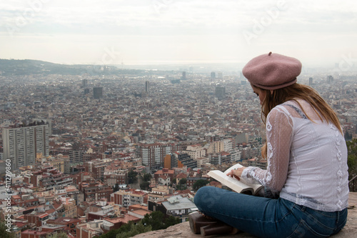 Canvas Print Woman quietly reads a book from a viewpoint in the city of Barcelona