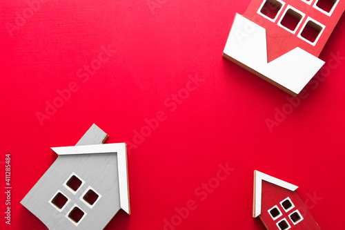 Wooden models of houses. Rent, buying or mortgage concept. Red background. Copy space. photo