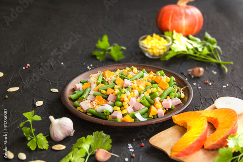 Delicious healthy pumpkin salad with corn and ham. Creative atmospheric decoration