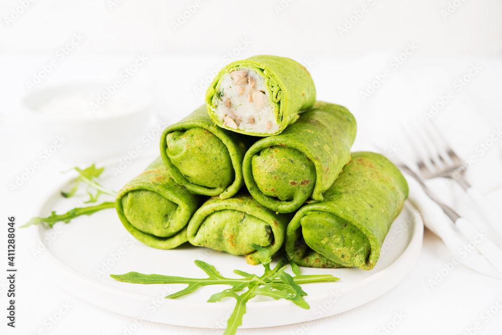 Homemade green vegetarian pancakes with filling ( potatoes and mushrooms), vegetable food, spinach pancakes on a white background Homemade green vegetarian pancakes with filling ( potatoes and mushrooms), vegetable food, spinach pancakes on a white background