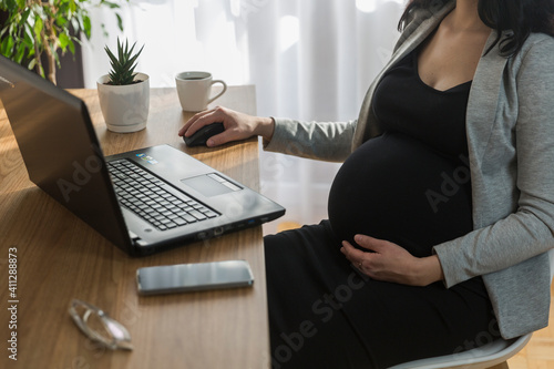 фотографія Pregnant woman is working on computer laptop and mobile phone, business