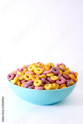 Vertical shot of multicolored fruity cereals in a blue bowl isolated on white background