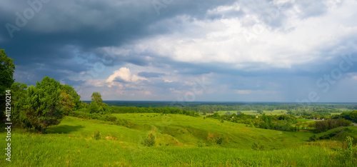 wide green hills under a dense cloudy sky, summer rural scene