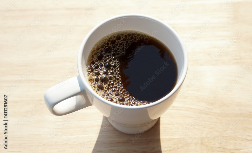 White cup of black coffee and spoon isolated on wooden background White cup of black coffee and spoon isolated on wooden background