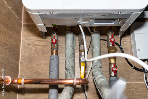 Natural gas valves and pipes in a modern home boiler room with ceramic tiles.