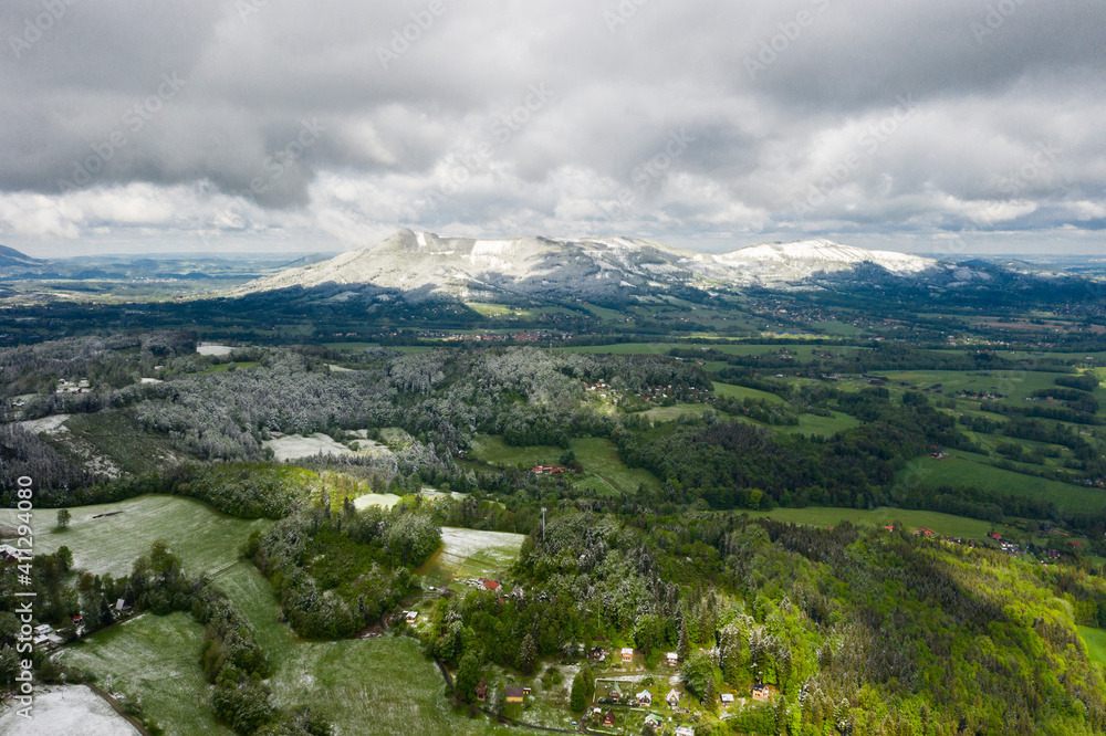 Mountains in the Czech Republic in spring with green fields and snow in the mountains 