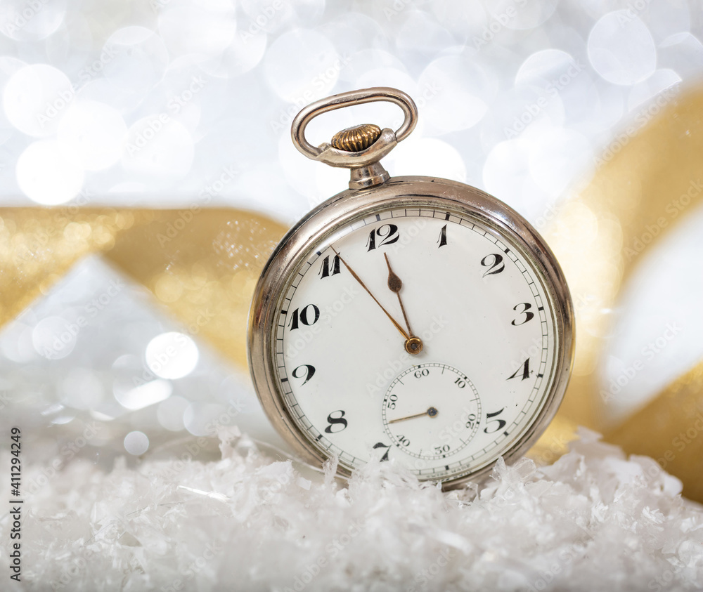 New Years eve countdown. Almost midnight on an old pocket watch, bokeh background.