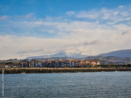 Hendaye traditional French village by the Cantabrian sea, Mount La Rhune Larrun covered by the snow at winter time. Landscape pictured from Hondarribia, Basque Country, Pyrenees, Spain