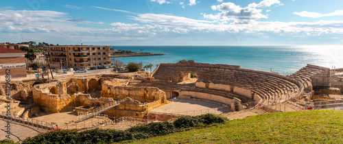 Ruins of ancient Roman amphitheater built during the Roman empire, Romanesque church inside, city of Tarraco - Tarragona, Catalonia, Spain, by the Mediterranean sea. Full view panoramic picture