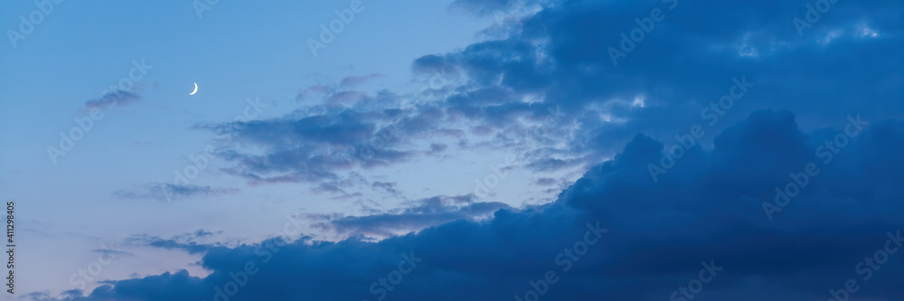 Beautiful sunset sky background with clouds and moon. Scenic cloudscape. Wide panoramic background for design. Beautiful sunset sky background with clouds and moon. Scenic cloudscape. Wide panoramic background for design.