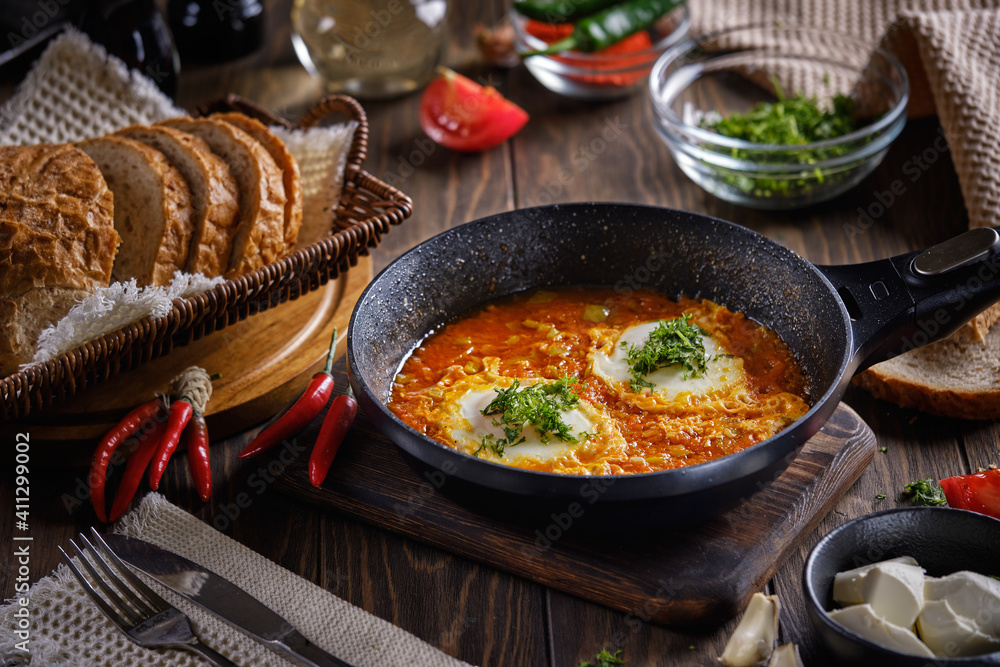 Turkish Scrambled Eggs with Tomatoes and Peppers in a frying pan on wooden table close-up