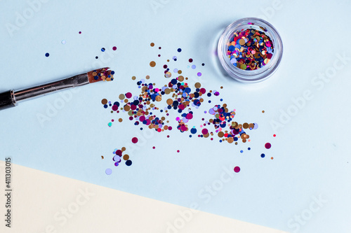 Set of cosmetic tools for manicure and pedicure on a yellow and blue background. Makeup bone, sequins, top view.