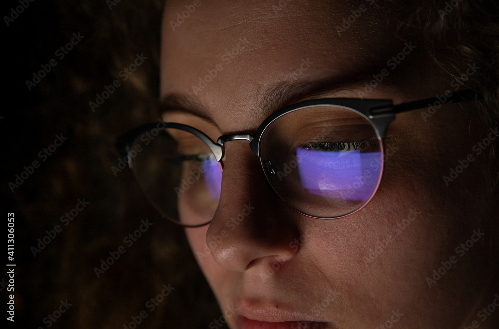 Reflection of a computer screen in glasses of a woman who is working at night. Reflection of a computer screen in glasses of a woman who is working at night.