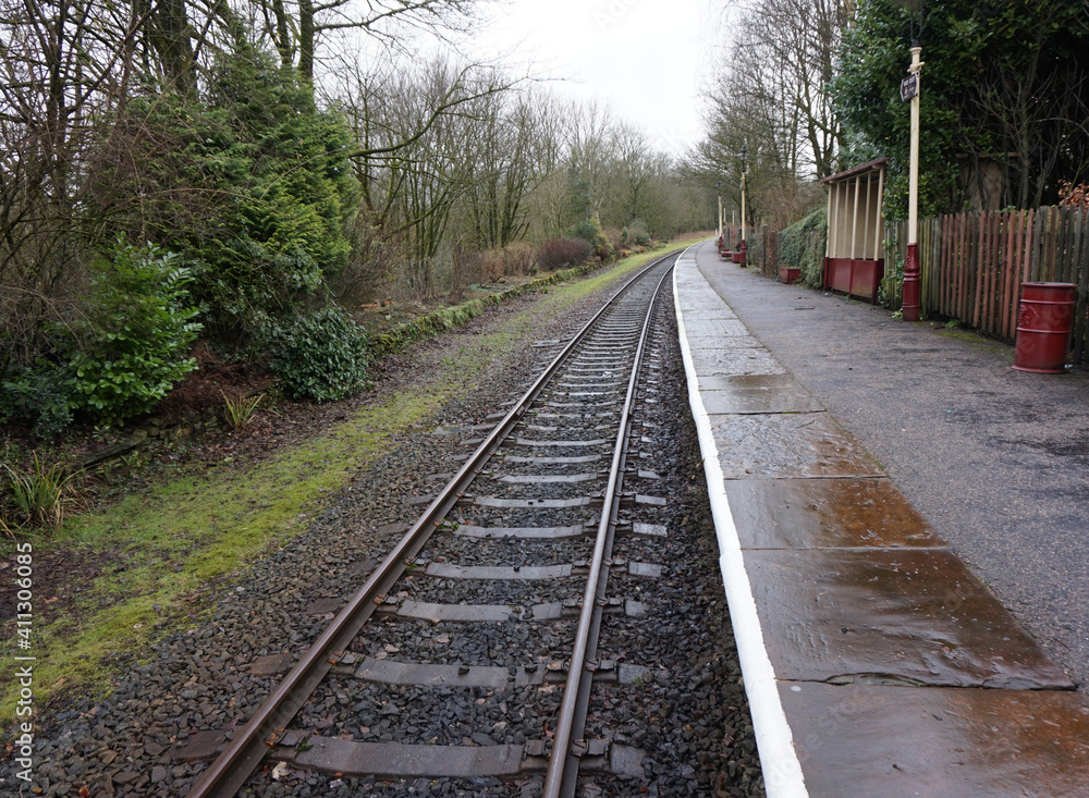 Rural single railway track and train station on a rainy day