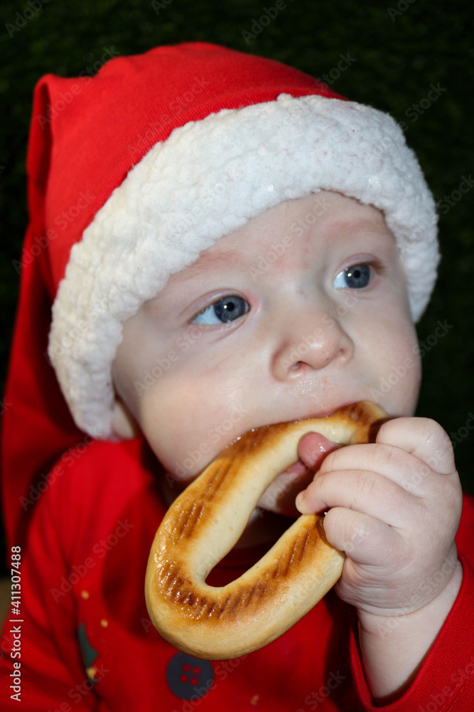 christmas gift - cute smiling child in red santa hat in the cardboard box eating the bagel close up portrait christmas gift - cute smiling child in red santa hat in the cardboard box eating the bagel close up portrait