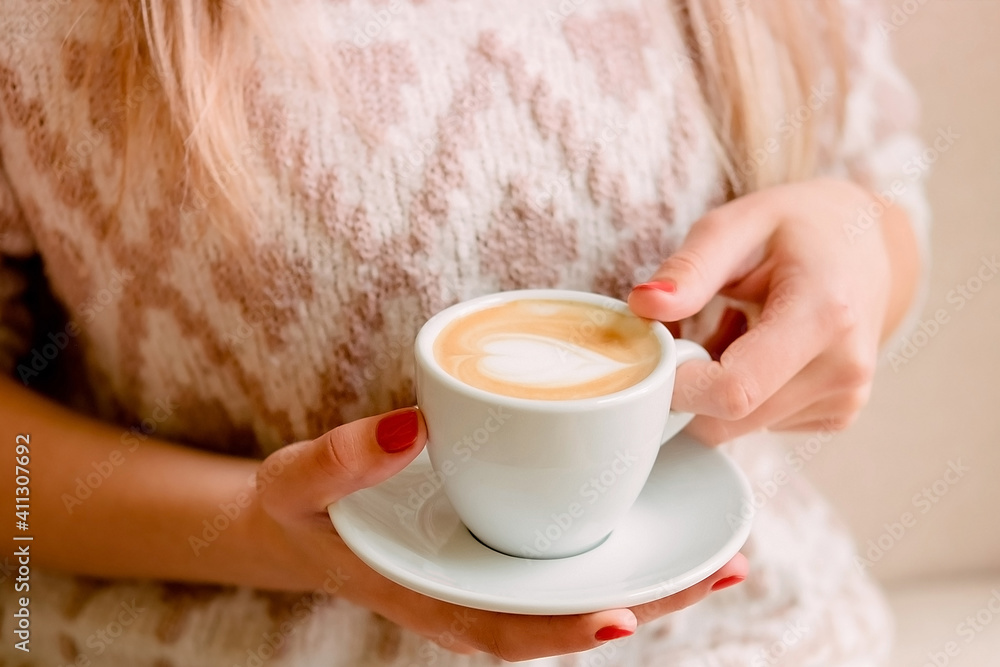 girl in a light knitted sweater sits on a sofa and holds a cup of coffee.. girl in a light knitted sweater sits on a sofa and holds a cup of coffee..