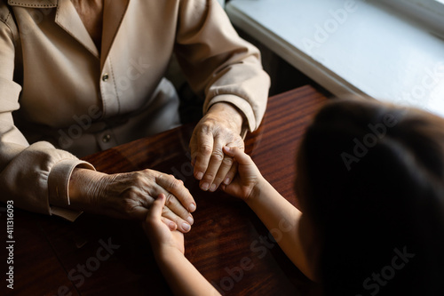 Fototapeta Naklejka Na Ścianę i Meble -  Young granddaughter taking care of grandmother with tender and care. Wrinkled hands of very old woman and young hands of teen woman close up, the change of family generation. Healthcare and wellness.