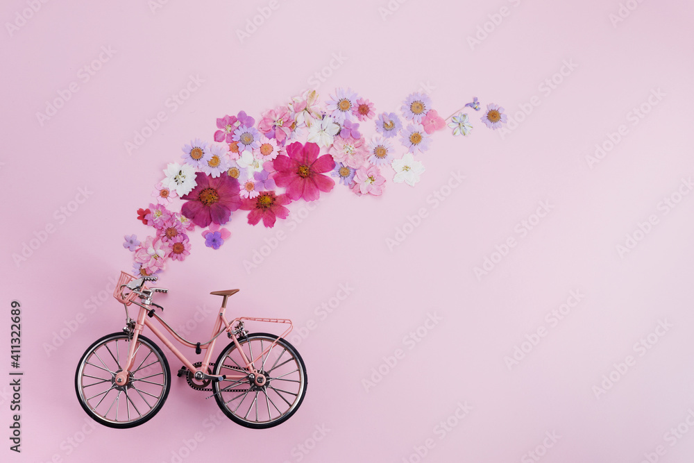 Flowers fly out from pink bicycle bascet on pink background. Romanitic concept for Valentine day, women or mother day. - obrazy, fototapety, plakaty 