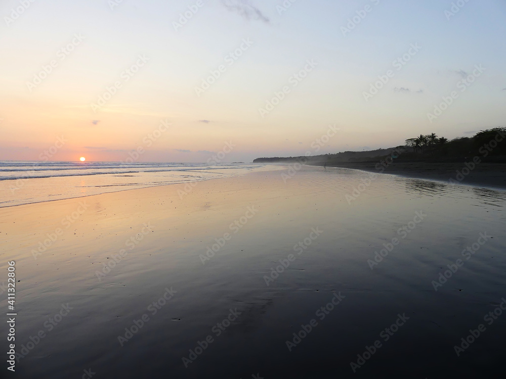 Beautiful sunset at the beach, with large water mirror reflecting the sky. In the Pacific coast of Costa Rica.