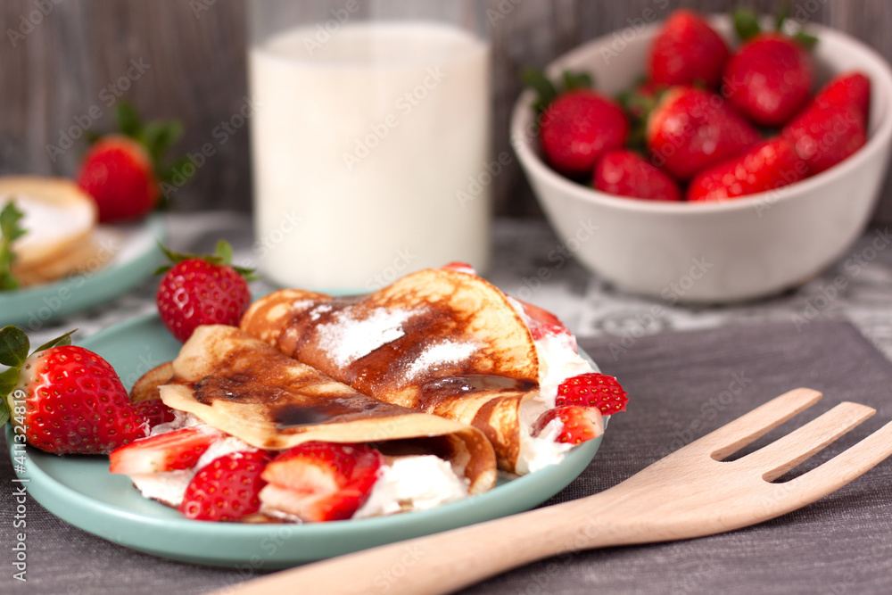 Bodegón de un plato de crepes con nata y fresas, un cuenco de fresas y una botella de leche en el fondo. Bodegón de un plato de crepes con nata y fresas, un cuenco de fresas y una botella de leche en el fondo.