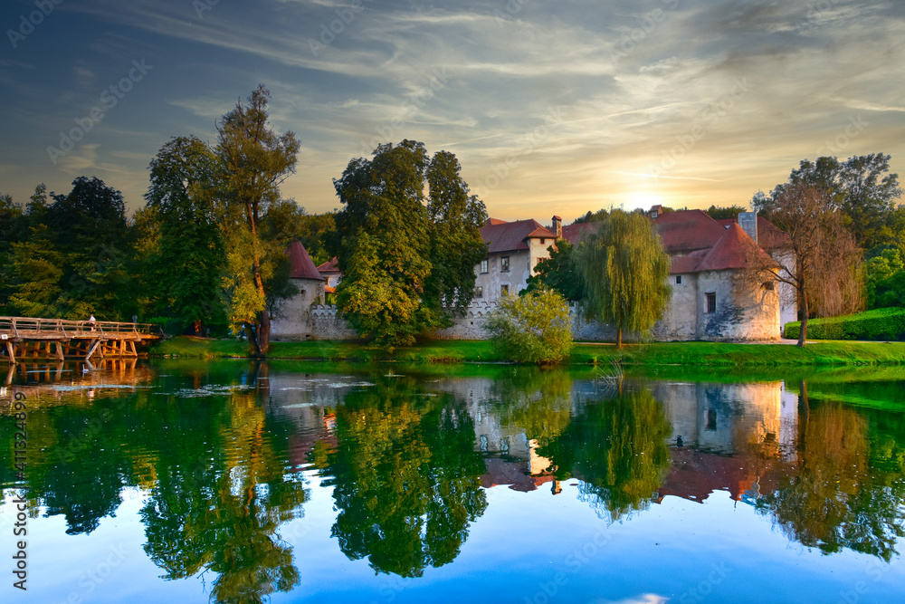 Obraz premium Castle Otočec on the river Krka in southern Slovenia, evening sunset scene with reflection of castle on the water