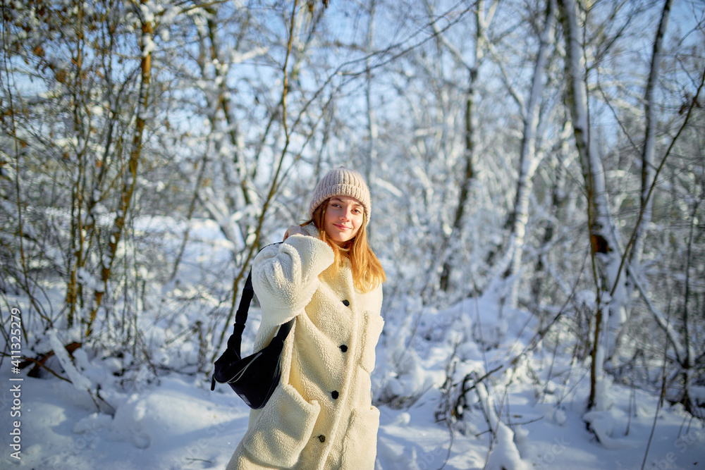 Young woman walks on the background of a snowy forest Young woman walks on the background of a snowy forest