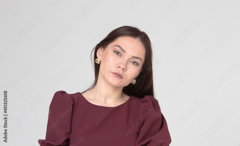 beautiful girl of 25 years old, European appearance, with dark long hair, in a burgundy dress, stands on a light gray background, in the studio. Portrait of a girl, brunettes, beauty, sad look beautiful girl of 25 years old, European appearance, with dark long hair, in a burgundy dress, stands on a light gray background, in the studio. Portrait of a girl, brunettes, beauty, sad look