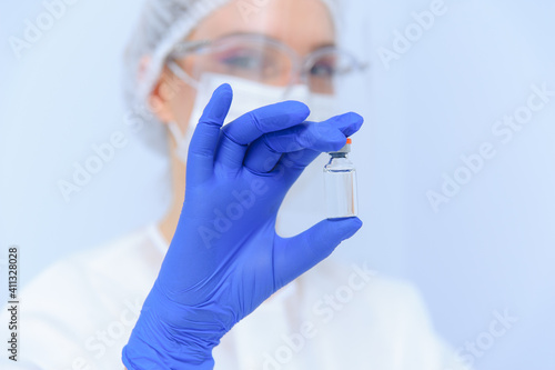 Doctor in medical gloves and a mask holds a vaccine in his hands