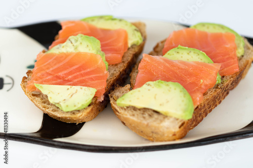 Homemade toast sandwich with salmon and avocado on a slice of cereal bread. The toast lies on a plate in the shape of a black and white panda. healthy food.