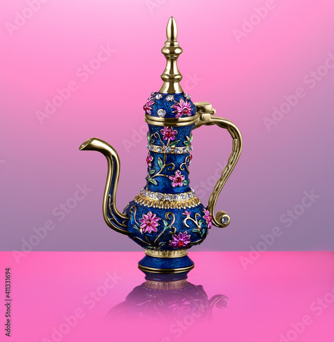 ornamented engraved oriental teapot with a long golden spout and a lid