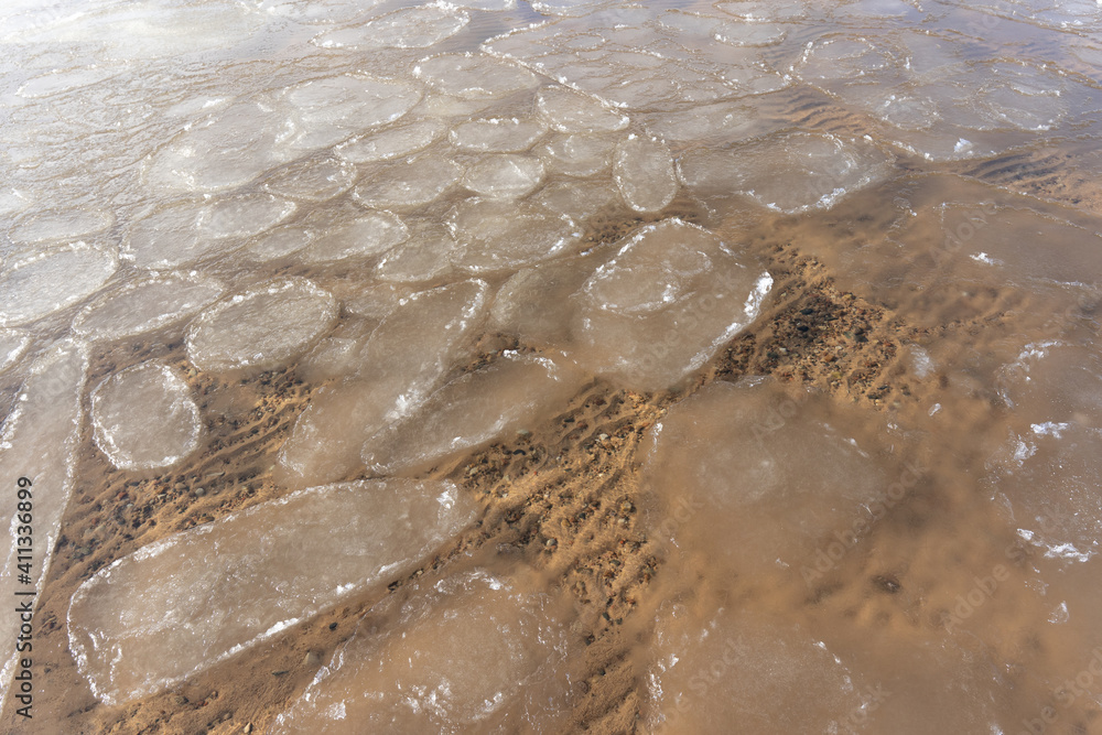 the water swirls and forms a texture through which you can see yellow sand and small stones the water swirls and forms a texture through which you can see yellow sand and small stones