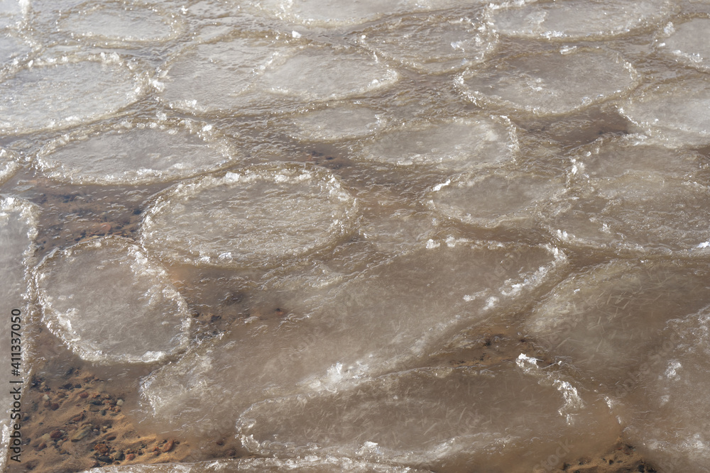 the water swirls and forms a texture through which you can see yellow sand and small stones the water swirls and forms a texture through which you can see yellow sand and small stones
