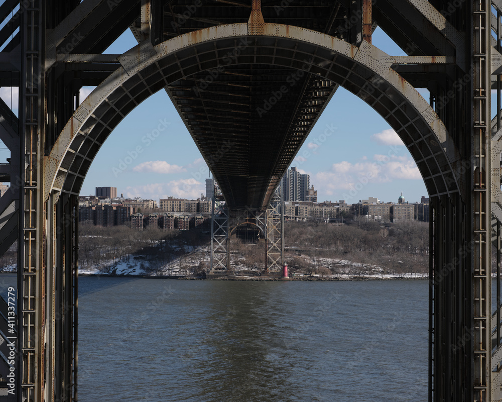 Fototapeta premium The underneath structure of the George Washington Bridge spanning New Jersey to New York with the Little Red Lighthouse on the shore on the New York Side