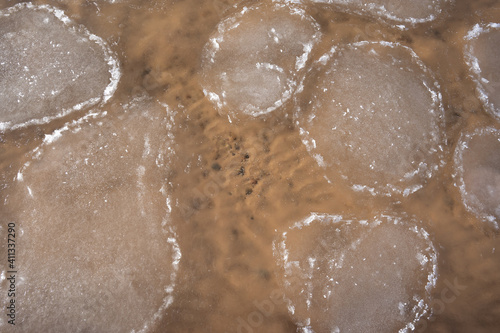 the water swirls and forms a texture through which you can see yellow sand and small stones